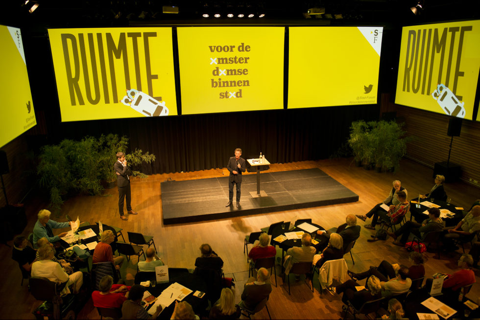 Foto van de bijeenkomst in Pakhuis de Zwijger waar het manifest van Stad-Forum werd gepresenteerd. Er is veel media-aandacht voor het manifest.